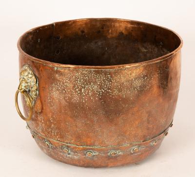 A copper cauldron with lion mask handles,