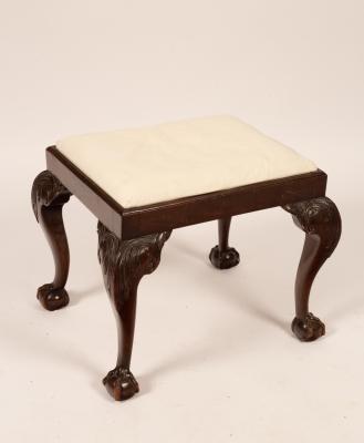 A rectangular stool on carved legs with