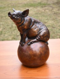 A bronze pig on ball, signed on