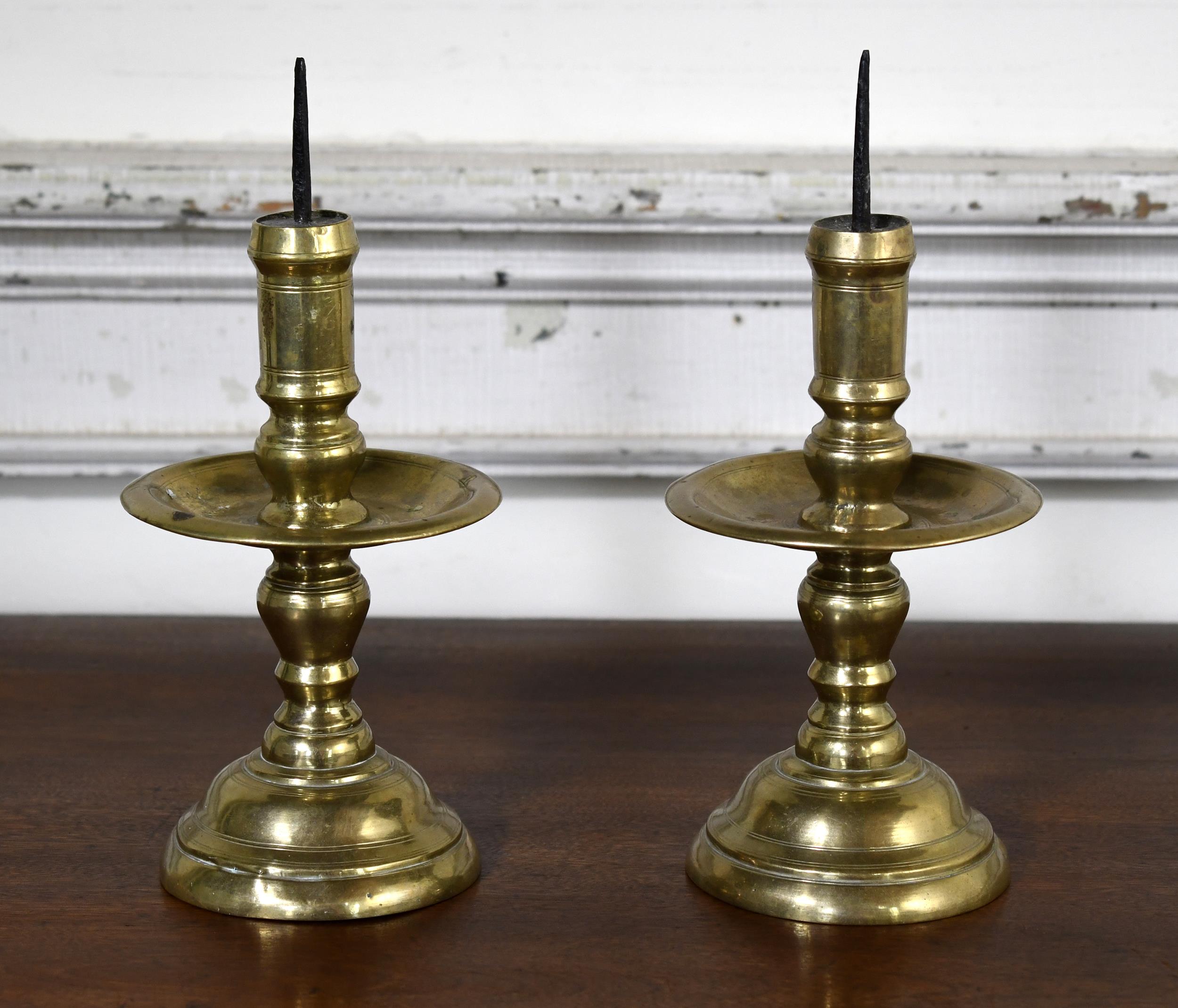 17TH C. MEDIAL DRIP BRASS CANDLESTICKS.