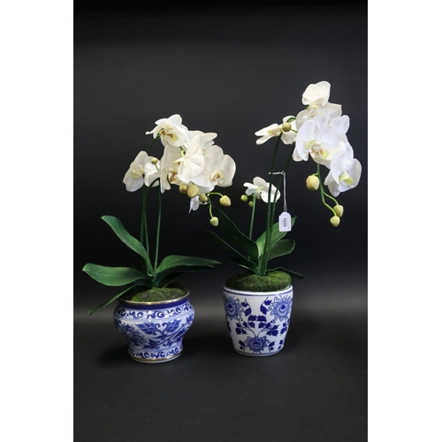 Two faux orchids in blue and white pots,