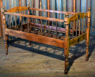 An antique folding spool turned crib,