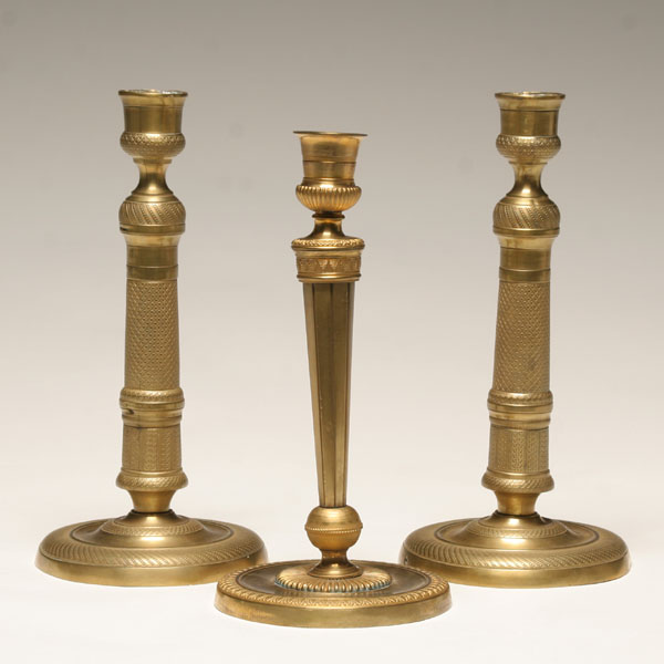 Three antique engraved brass candlesticks;