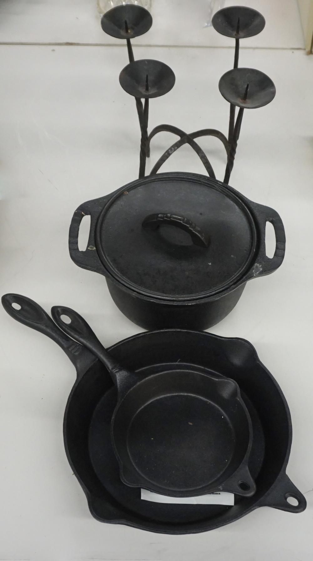 THREE CAST IRON PANS AND A CANDELABRUMThree