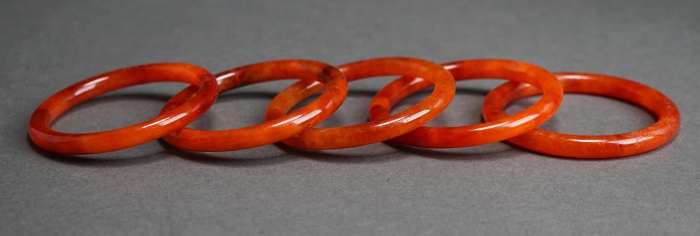 FIVE RED JADE BANGLE BRACELETS