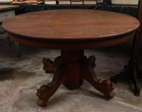 A ROUND OAK TABLE WITH CARVED LION