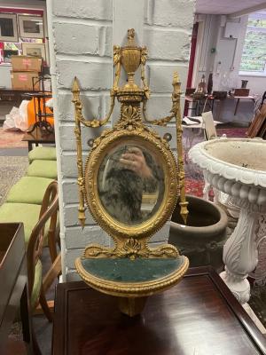 A gilt wall bracket with oval mirror