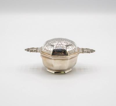 An octagonal silver tea strainer,