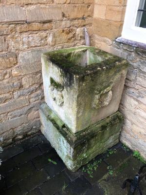 A stone planter on plinth with wreath