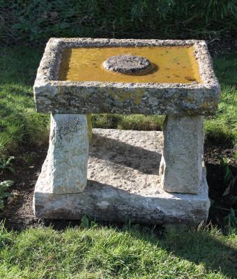 A stone bird bath on four turned