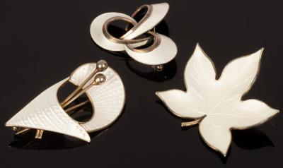 Three white enamel brooches, one of