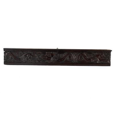 A carved oak panel with scrolls, foliage,