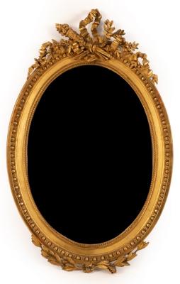 An oval gilt framed mirror surmounted