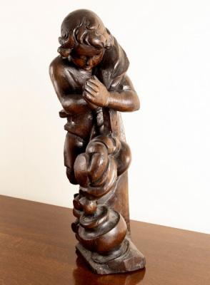 A carved oak wooden figure of a boy