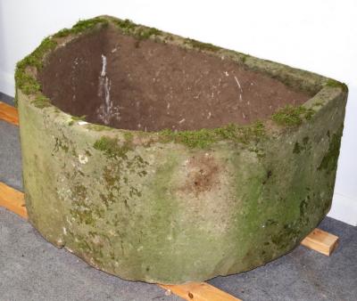 A large D-shaped stone trough,