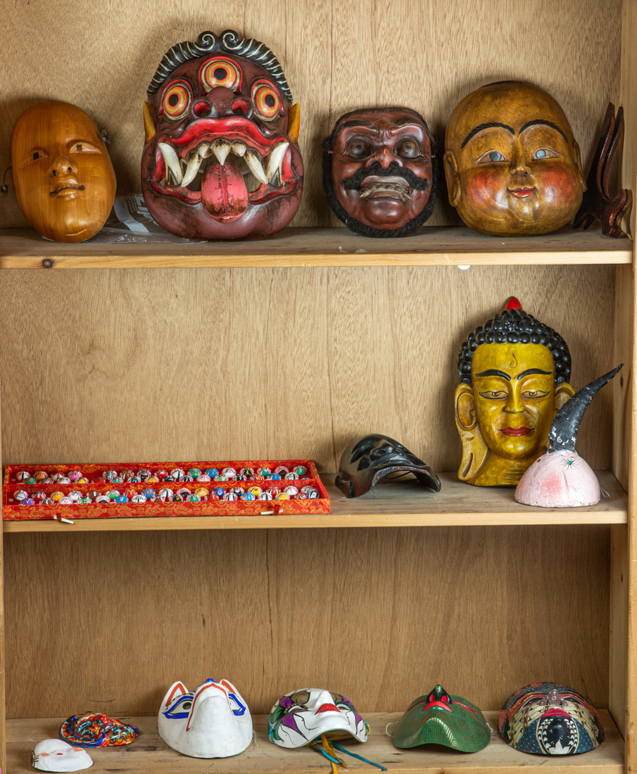 THREE SHELVES OF MOSTLY ASIAN MASKS