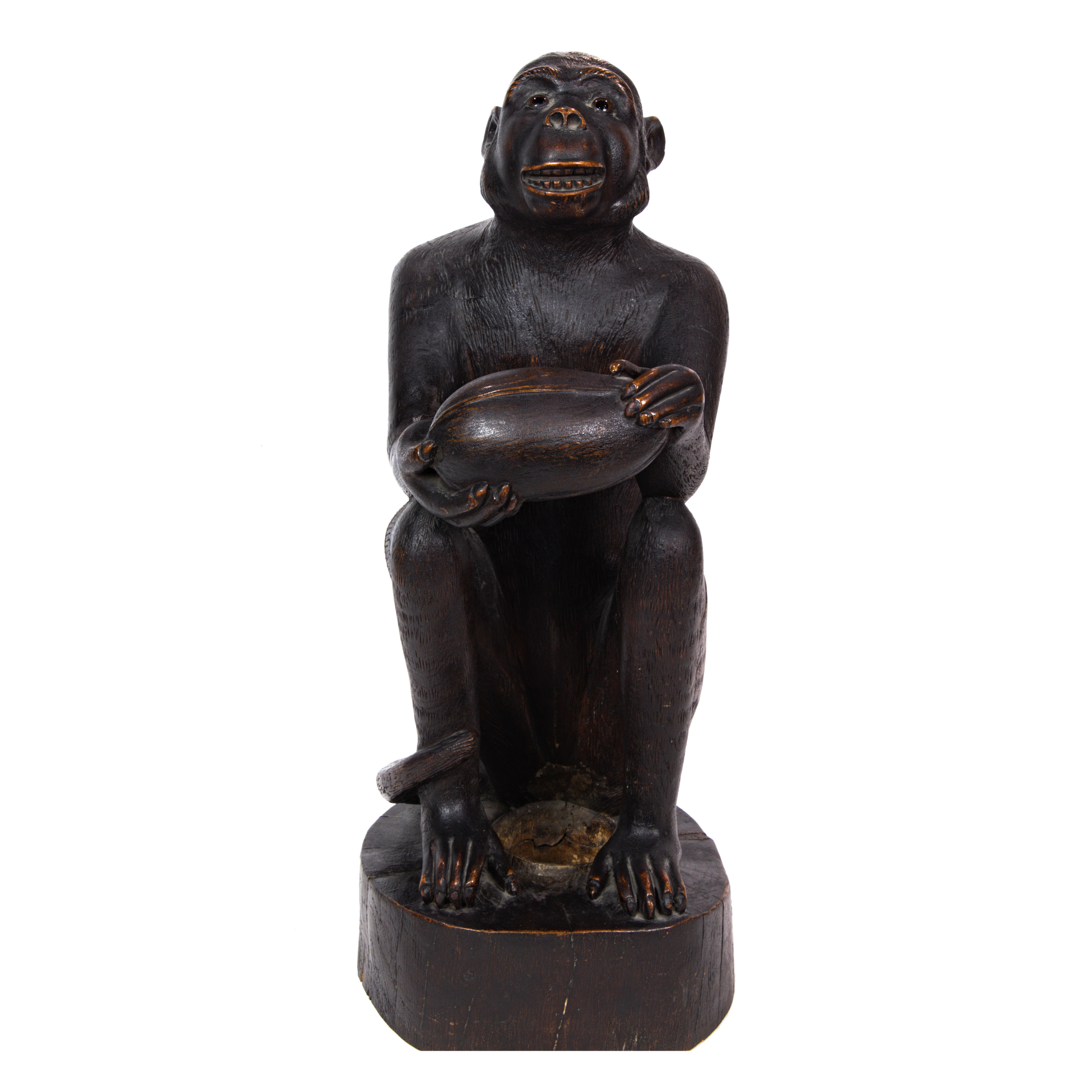 A CARVED MONKEY SEATED WITH COCONUT