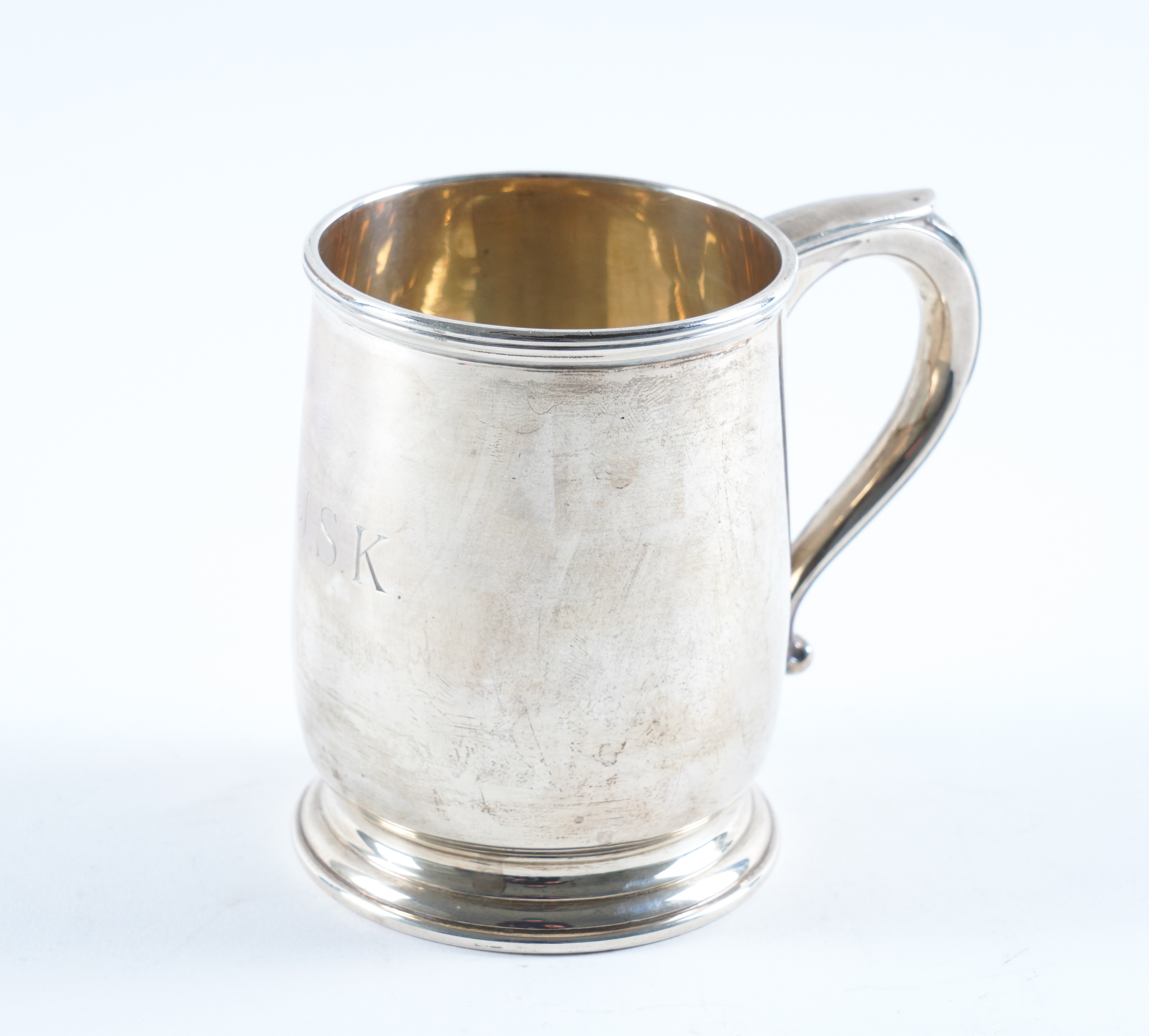 A SILVER MUG With a scrolled handle,