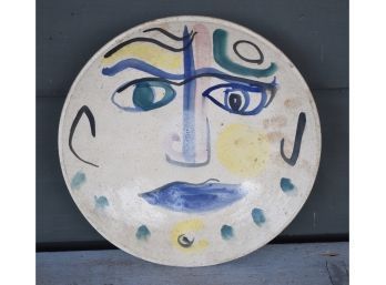 A signed plate with facial decoration
