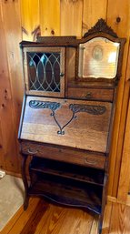 A vintage oak secretary desk with a