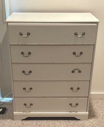 A contemporary white five drawer dresser.