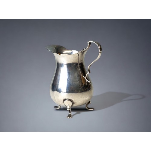 A sterling Silver tr-footed cream jug.Birmingham