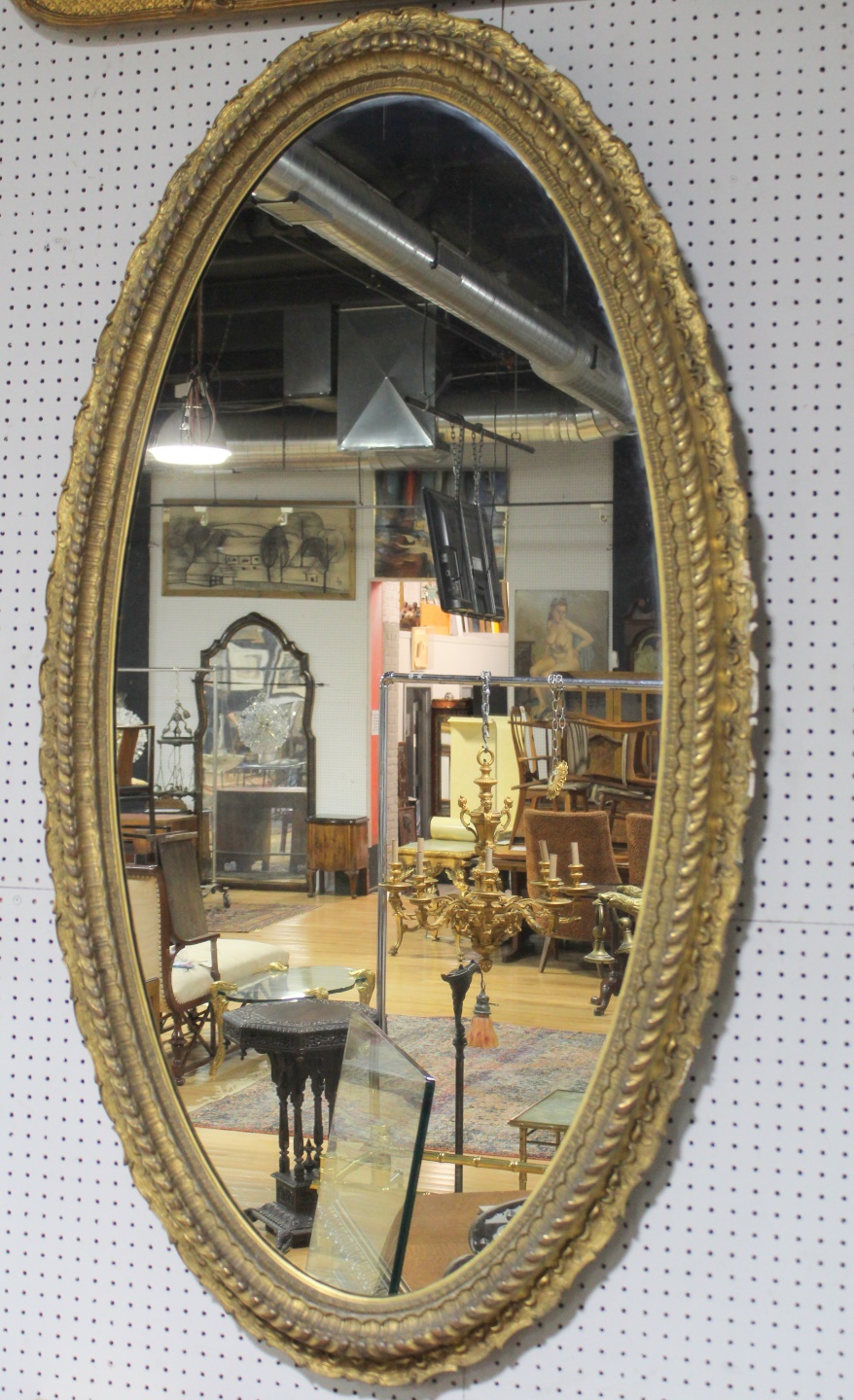A LARGE GILDED OVAL VICTORIAN MIRROR.