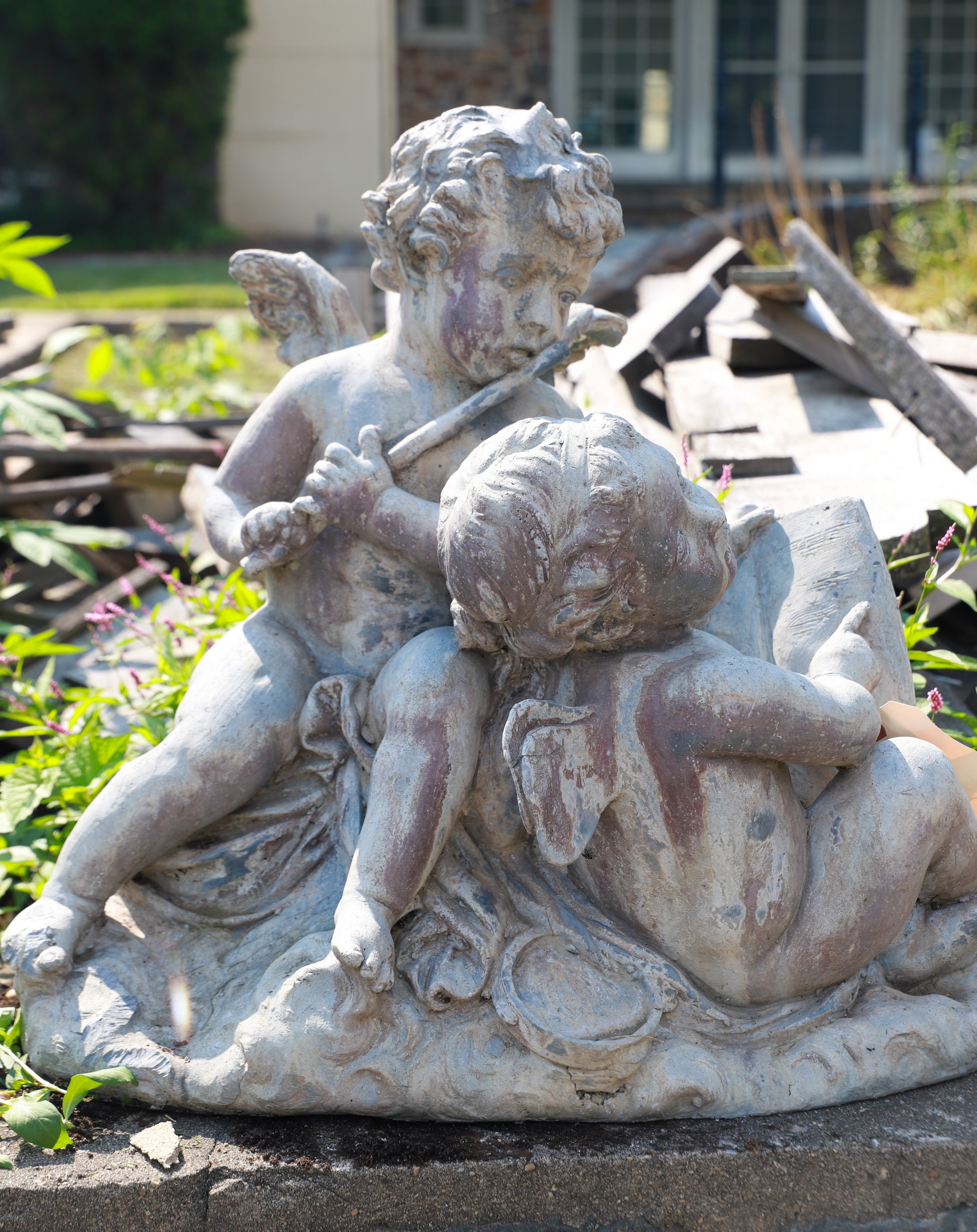 Garden statue of 2 cherubs, one reading