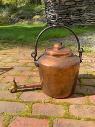 An antique copper kettle with a swing/bale