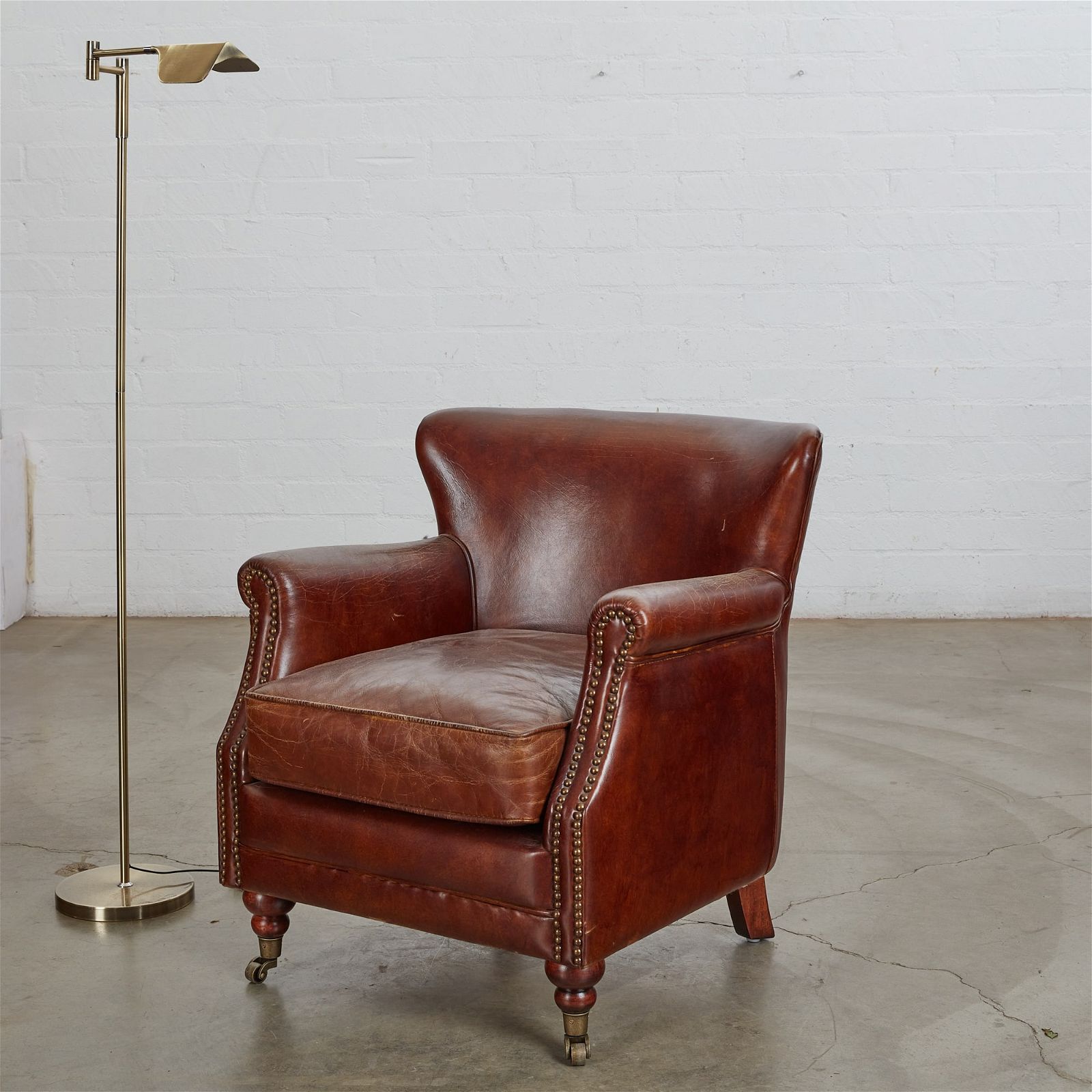 A BROWN LEATHER ARMCHAIR AND