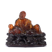 A CARVED AMBER FIGURE OF ARHAT