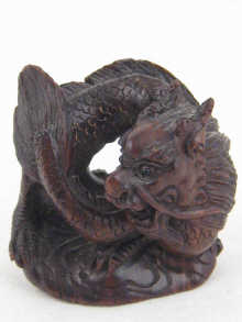 A carved wood netsuke with inlaid