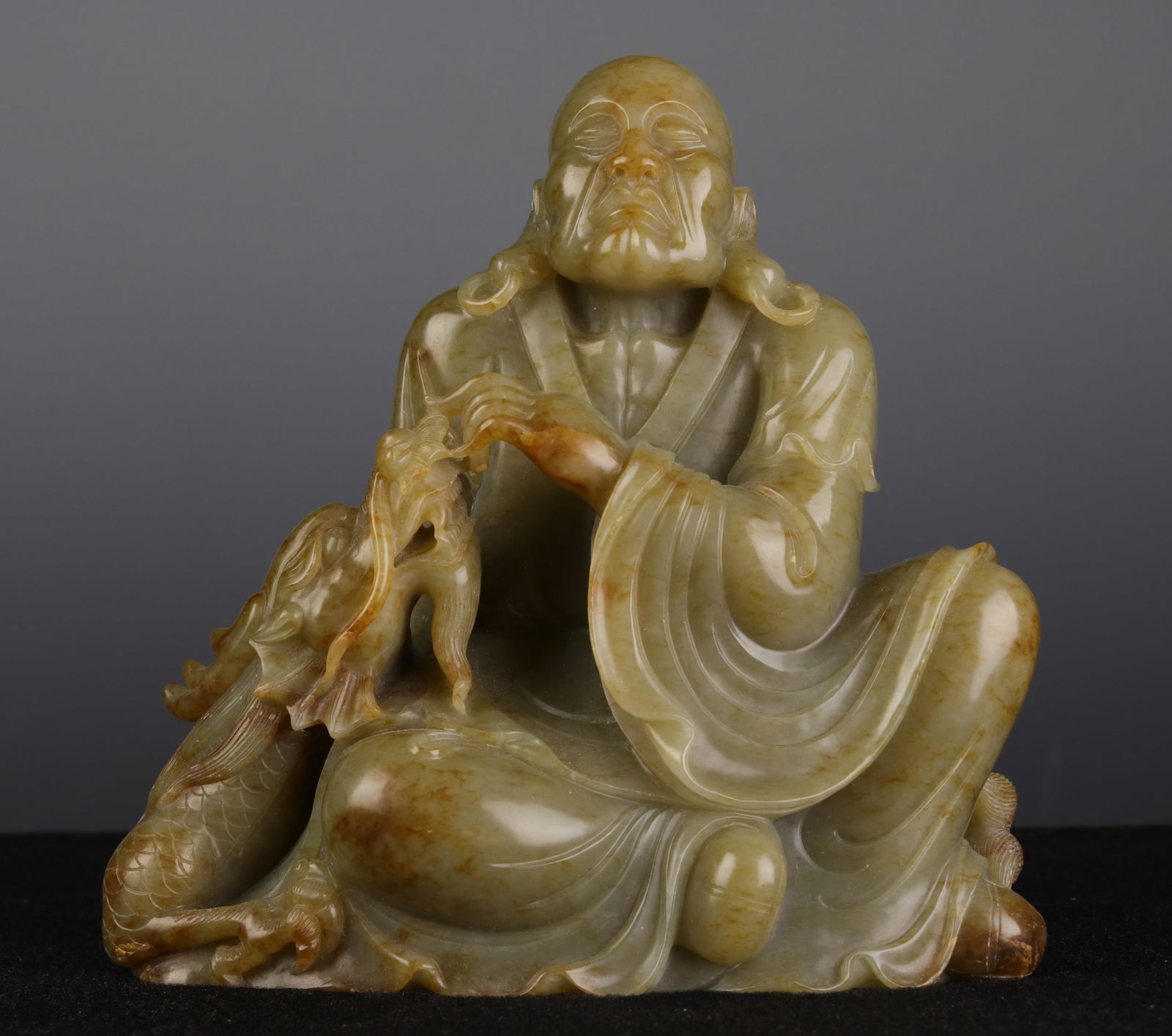 A CHINESE CARVED JADE SEATED FIGURE