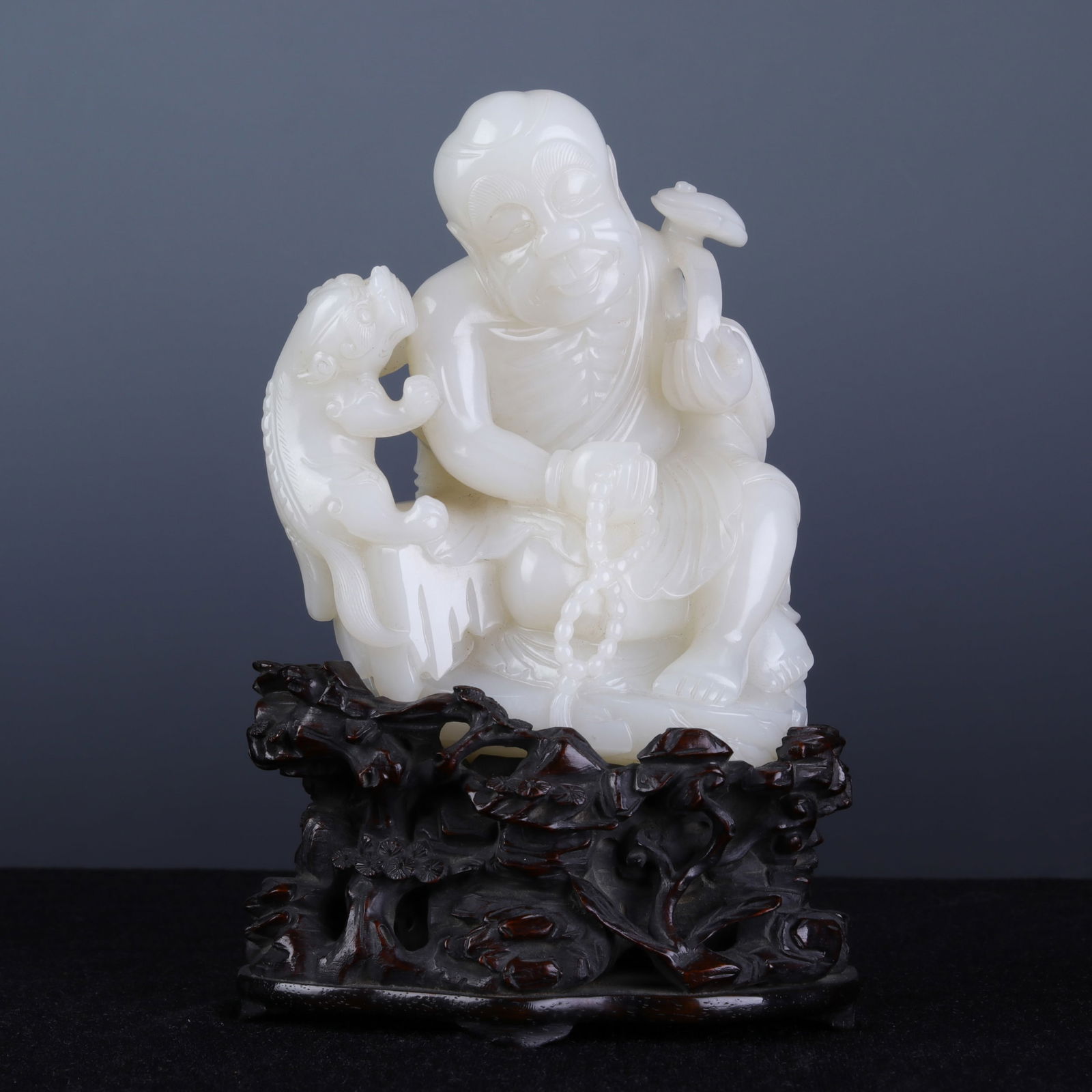 A CHINESE CARVED JADE SEATED FIGURE