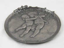 A circular pewter dish with putti