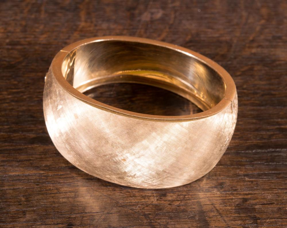 A HEAVY GOLD HINGED BANGLE