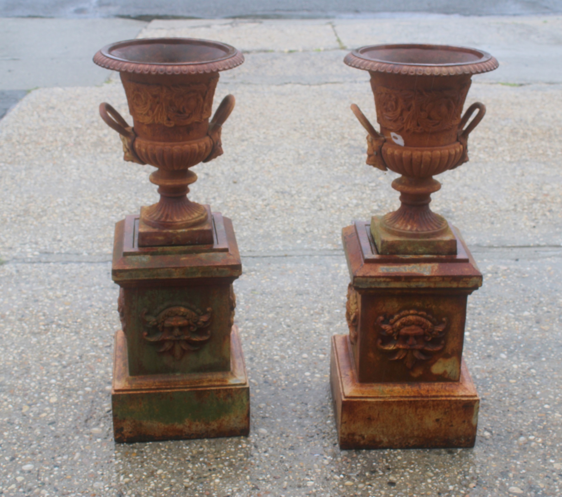 A PAIR OF CAST IRON URNS ON STANDS.