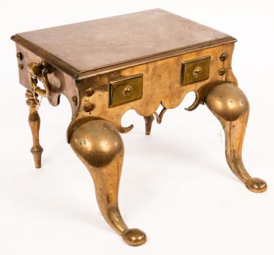 A plain brass trivet on cabriole