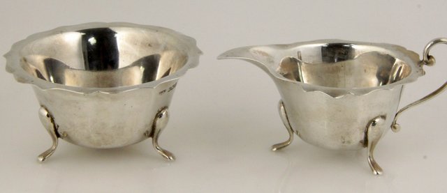 A silver cream jug and sugar