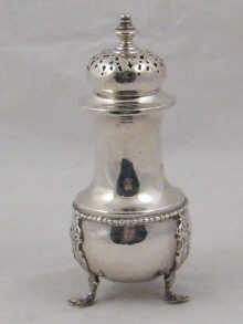 A silver sugar caster on three feet