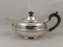 A silver teapot of flattened