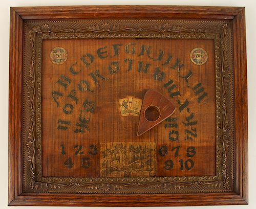 A WOOD OUIJA BOARD IN AN OAK FRAMEA