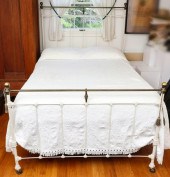 AN ANTIQUE IRON BED WITH BRASS