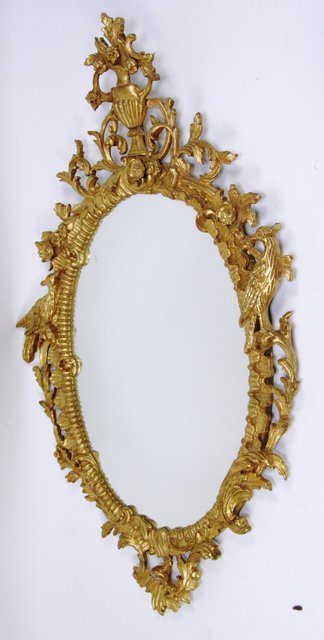 An oval wall mirror in a gilt