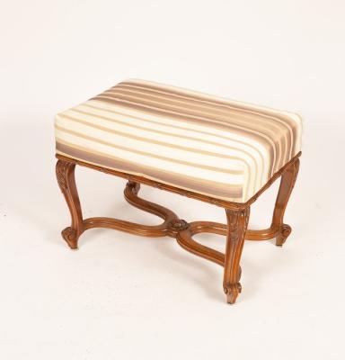 An upholstered foot stool on carved