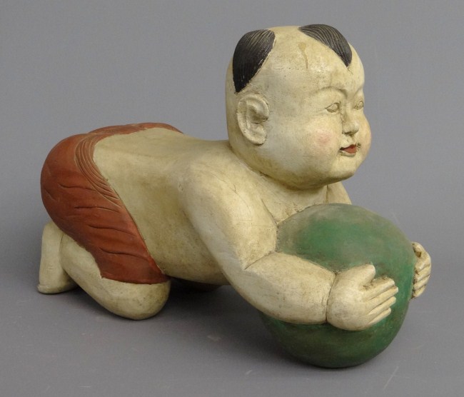 Asian wooden carving boy with ball.
