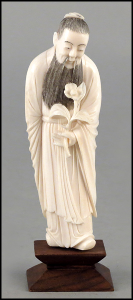 CARVED IVORY FIGURE HOLDING A