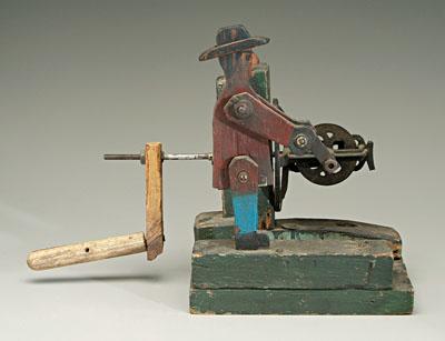 Folk art man turning crank, painted