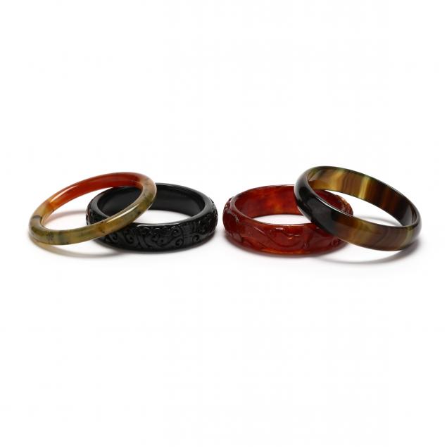 FOUR CARVED STONE BANGLES To