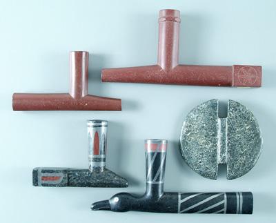 Four carved stone pipes: one red